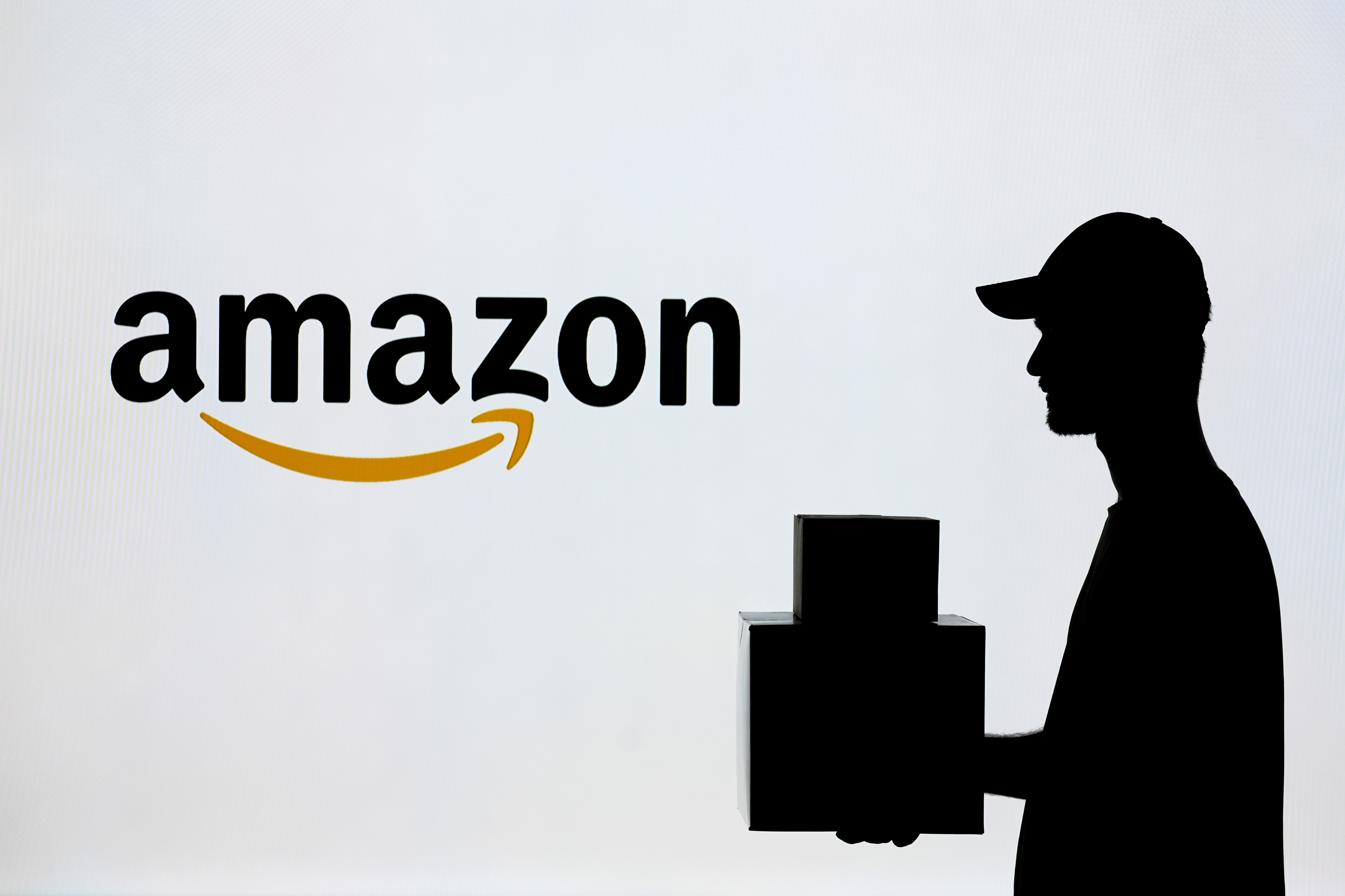 ANKARA, TURKIYE – JULY 4: In this photo illustration a man carrying a package in front of the Amazon logo in Ankara, Turkiye on July 4, 2024. (Photo by Dilara Irem Sancar/Anadolu via Getty Images)